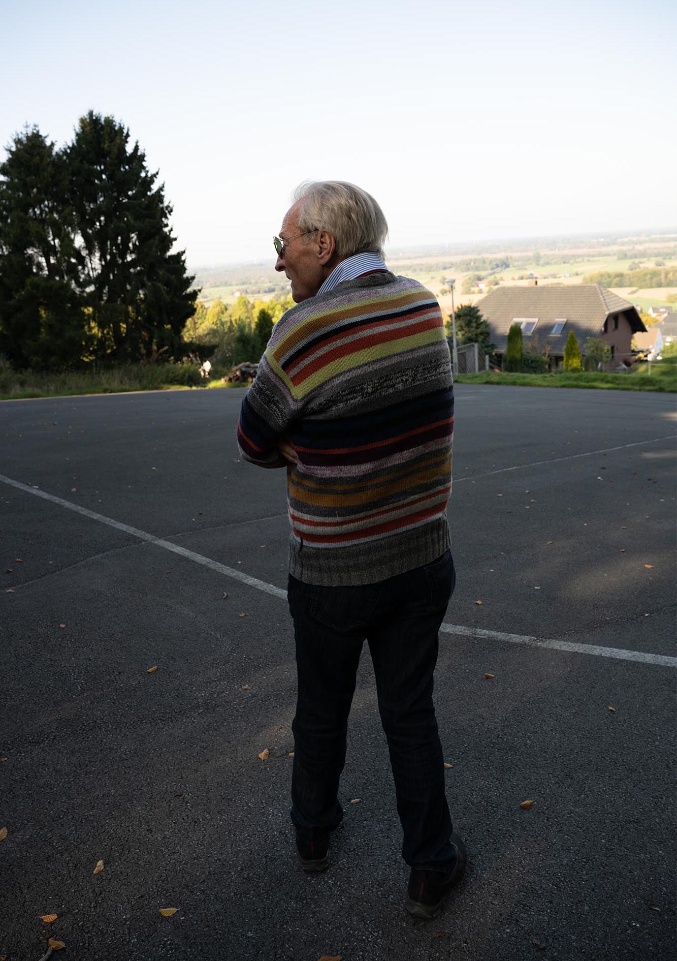 Die Katze steht auf einem Parkplatz mit dem Rücken zur Kamera