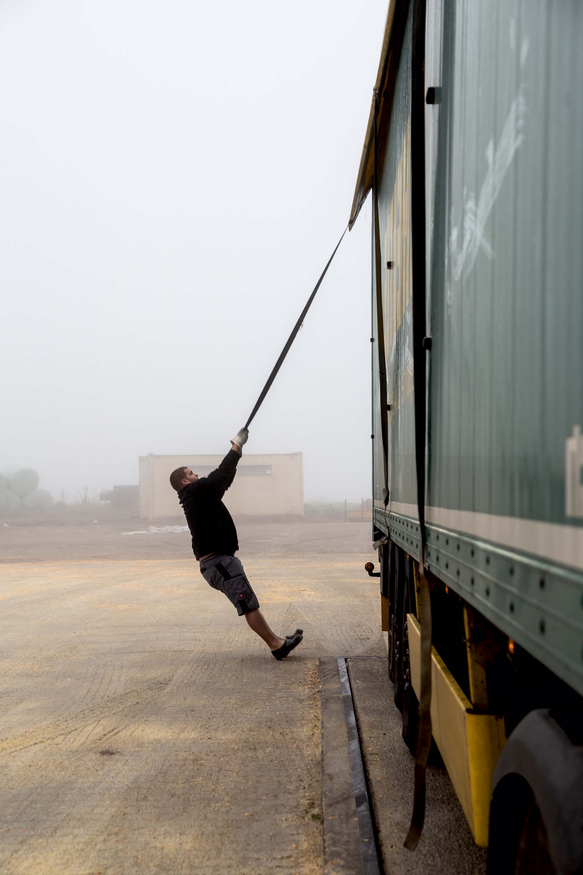 LKW-Fahrer Michl zurrt eine Plane im Nebel fest
